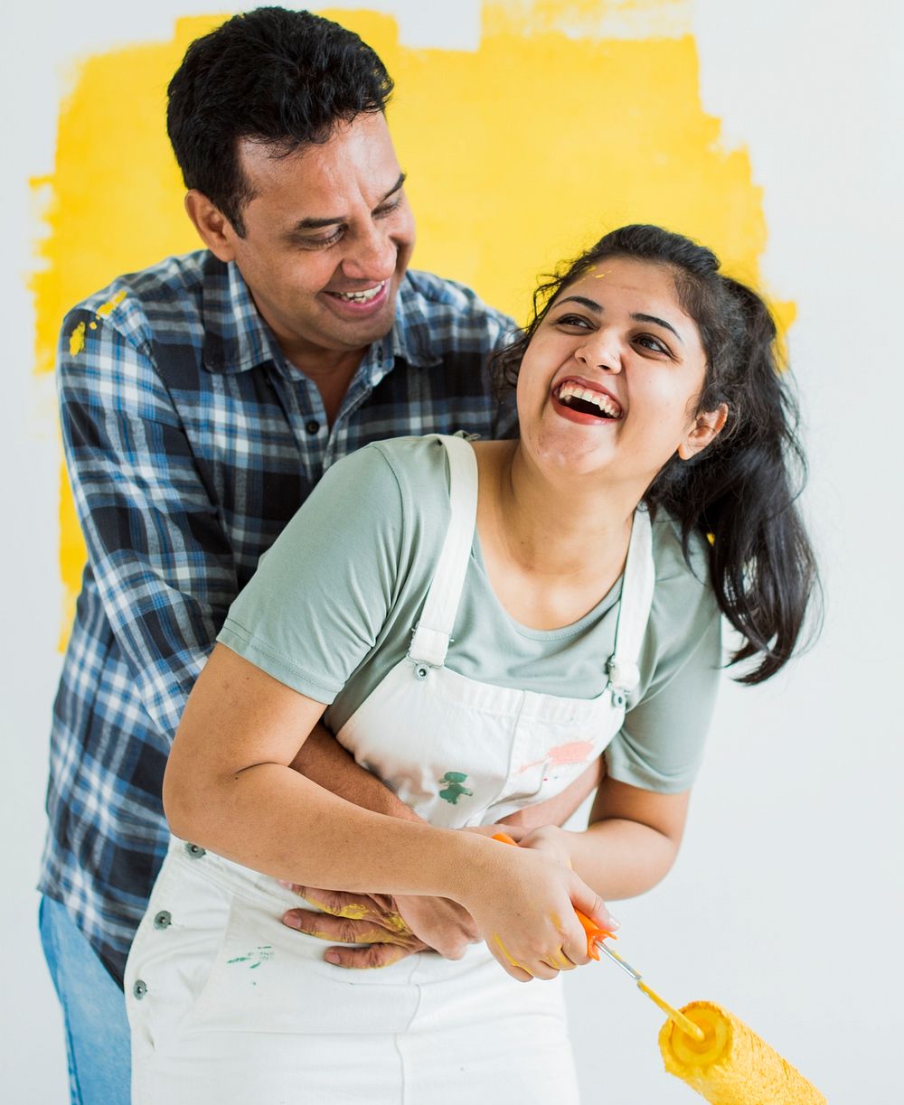 Cheerful couple painting the walls yellow