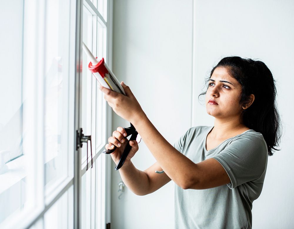 Woman using a silicone gun to repair a window
