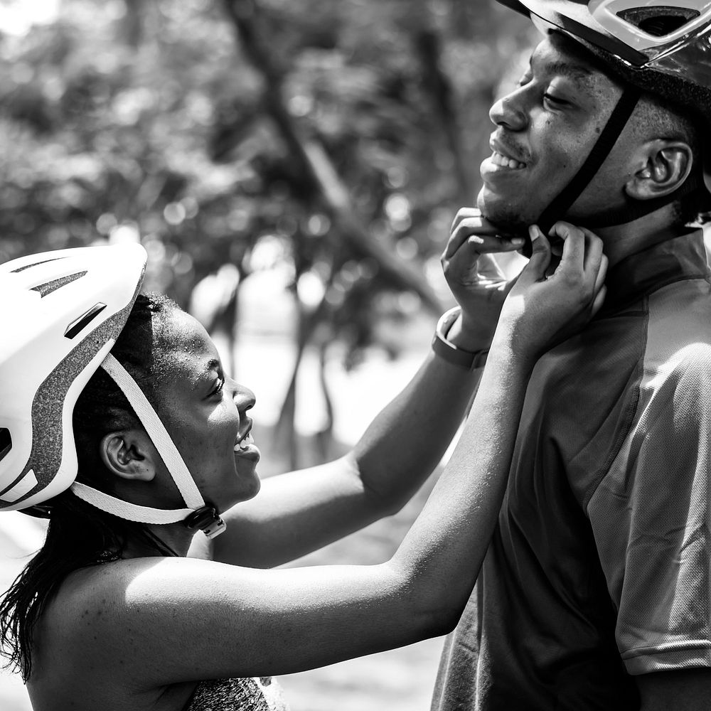 Woman fastens a bike helmet for her boyfriend