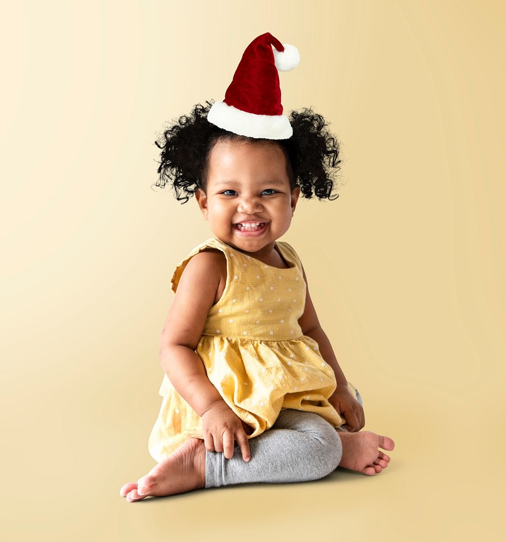 Happy little girl in a yellow dress with a Christmas hat