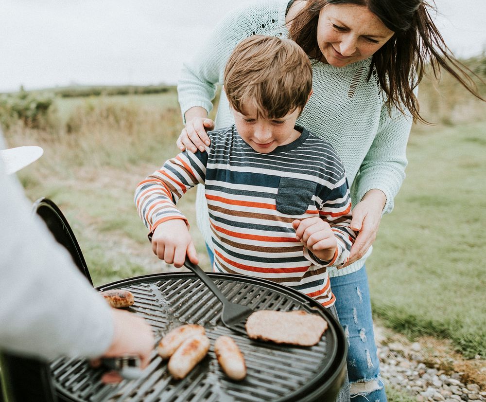 Mother assisting her child while grilling