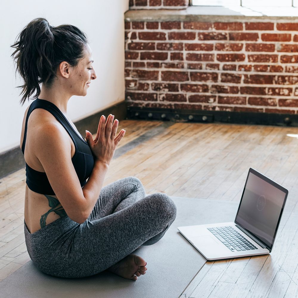 Sporty woman in Anjali Mudra pose with a laptop
