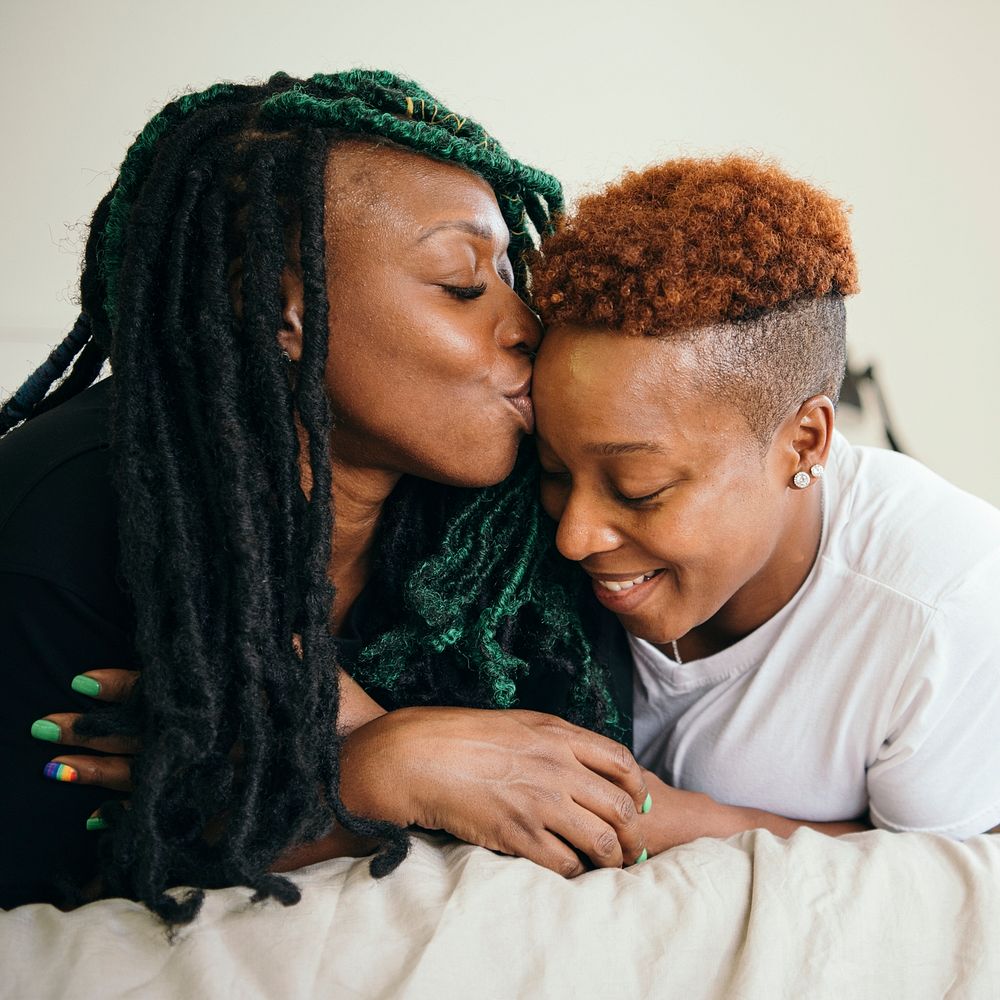 Happy lesbian couple smooching in bed