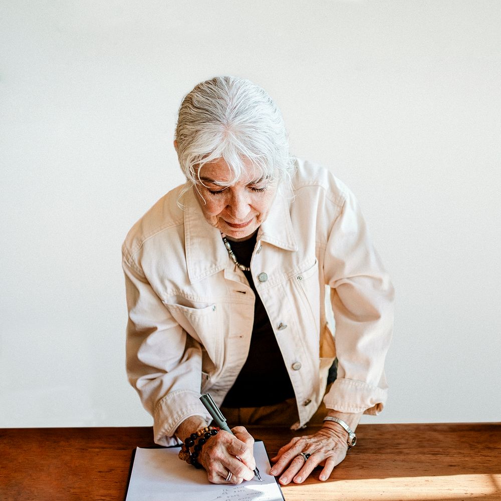 Elderly woman signing on a paper