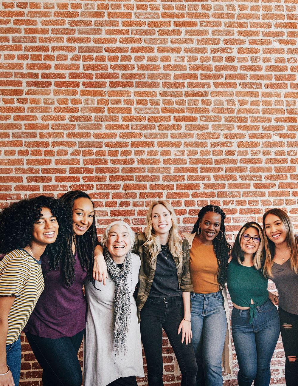Diverse women standing together by a brick wall