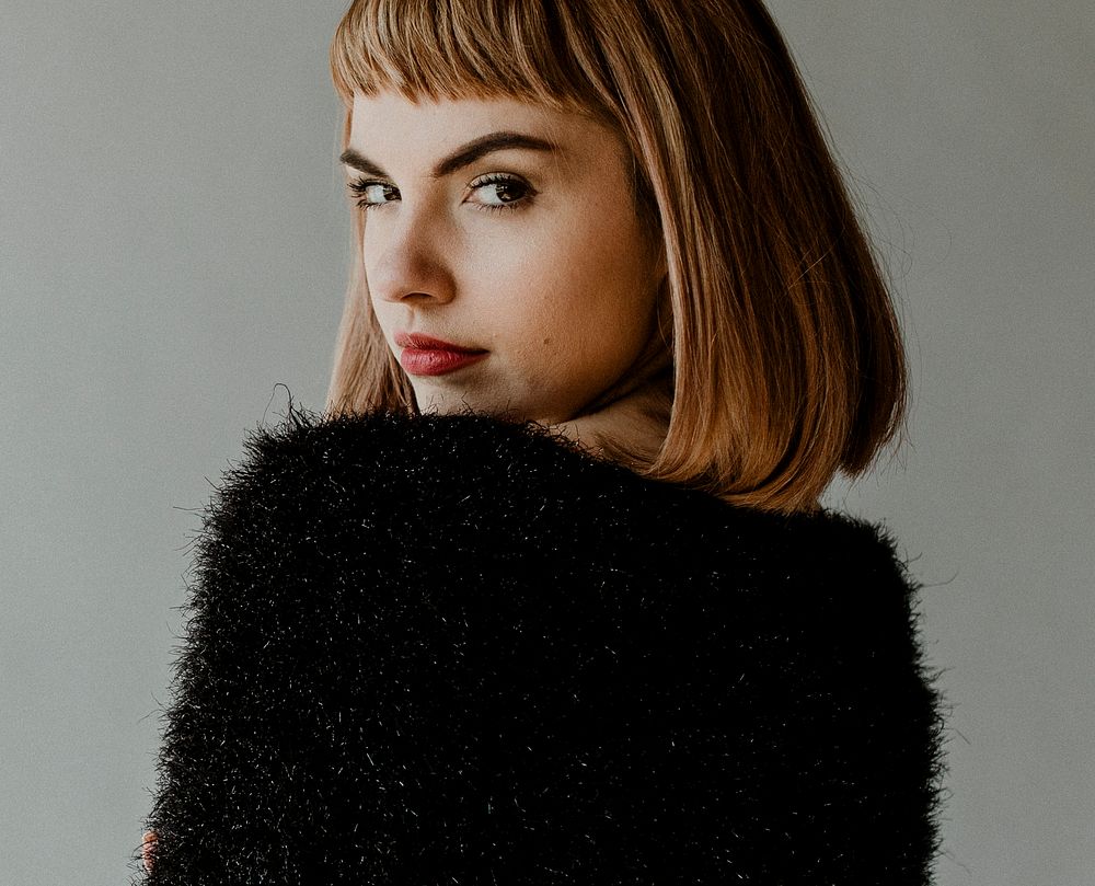 Brown hair woman in a black fluffy sweater looking back over her shoulder