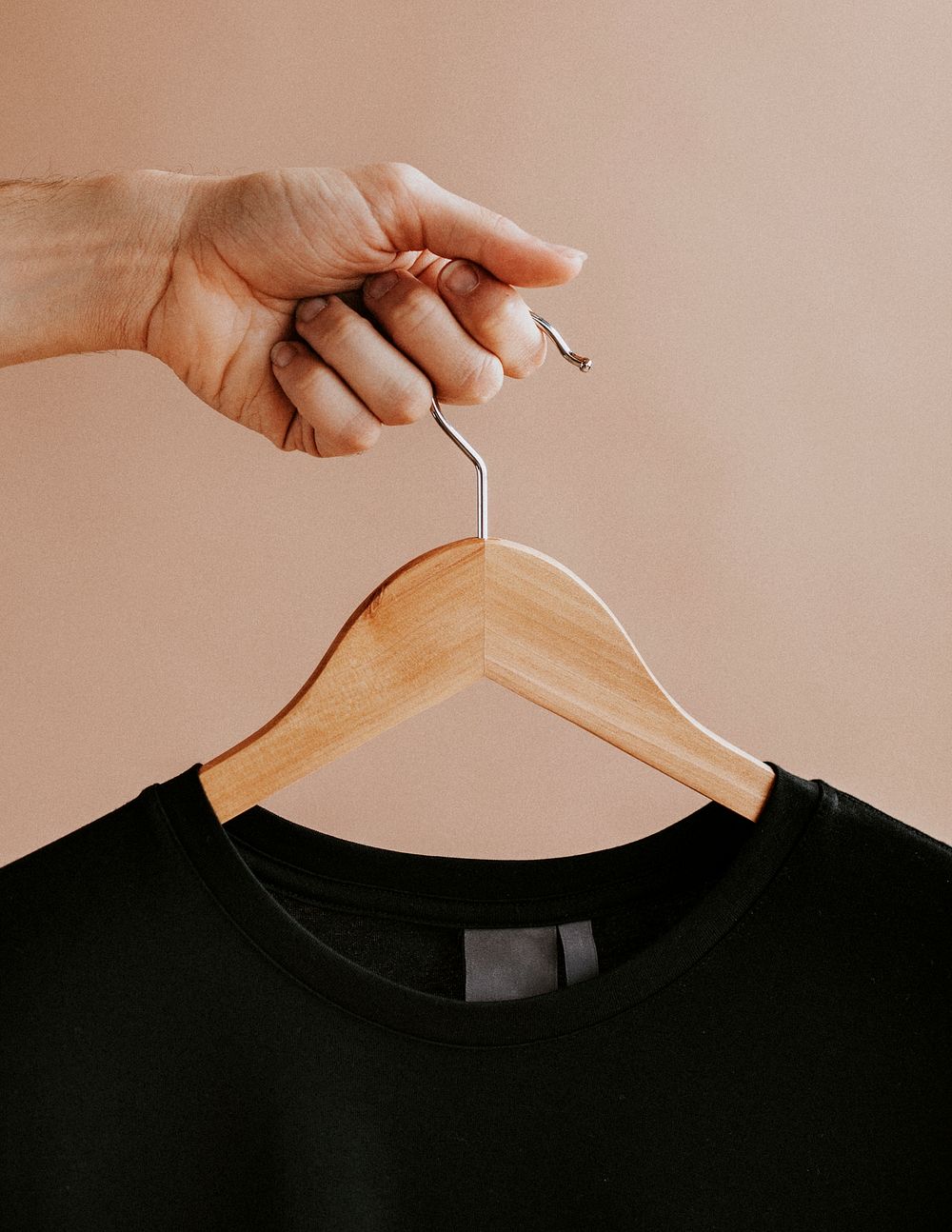 Hands holding a black t-shirt in a hanger