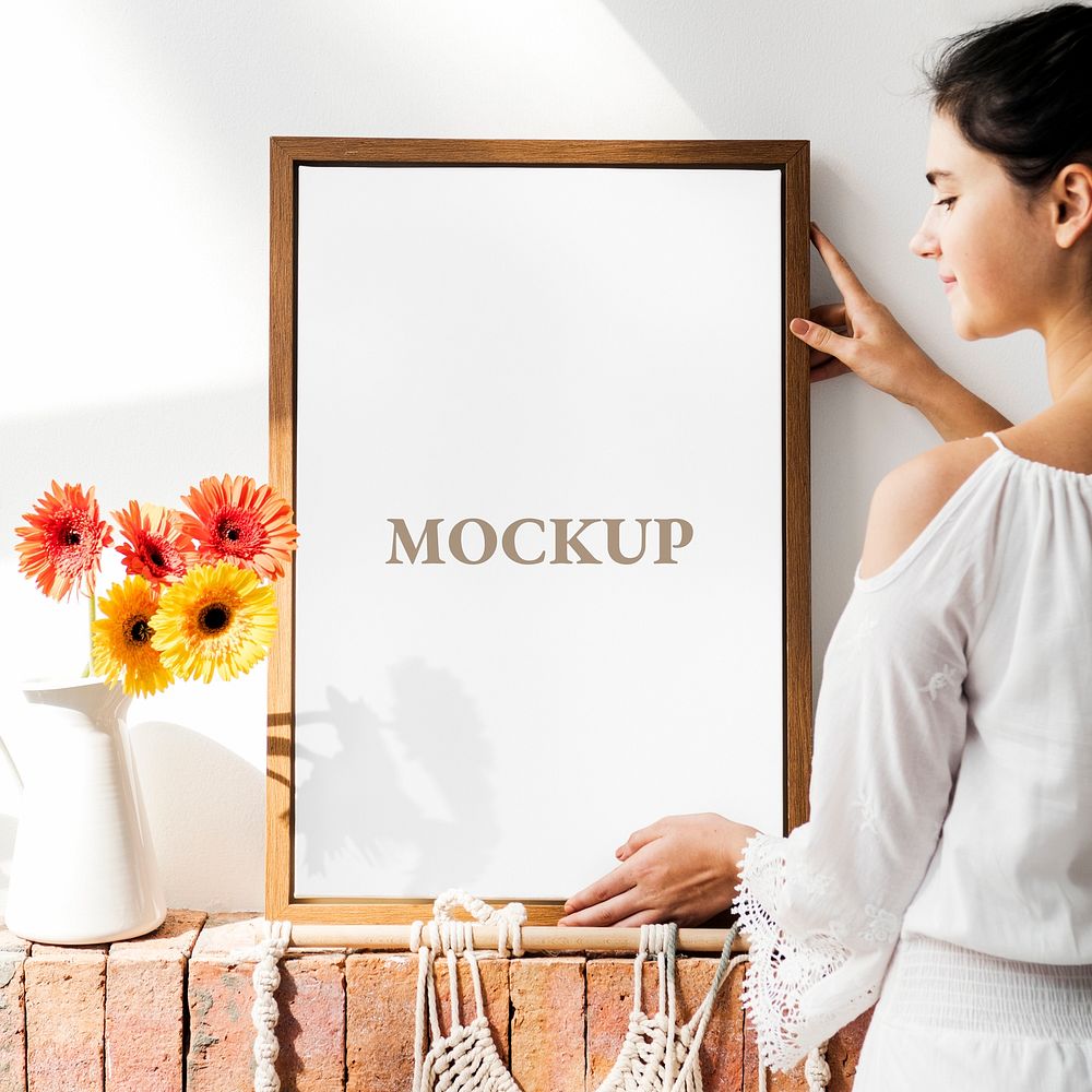 Girl decorating a wall with a frame mockup