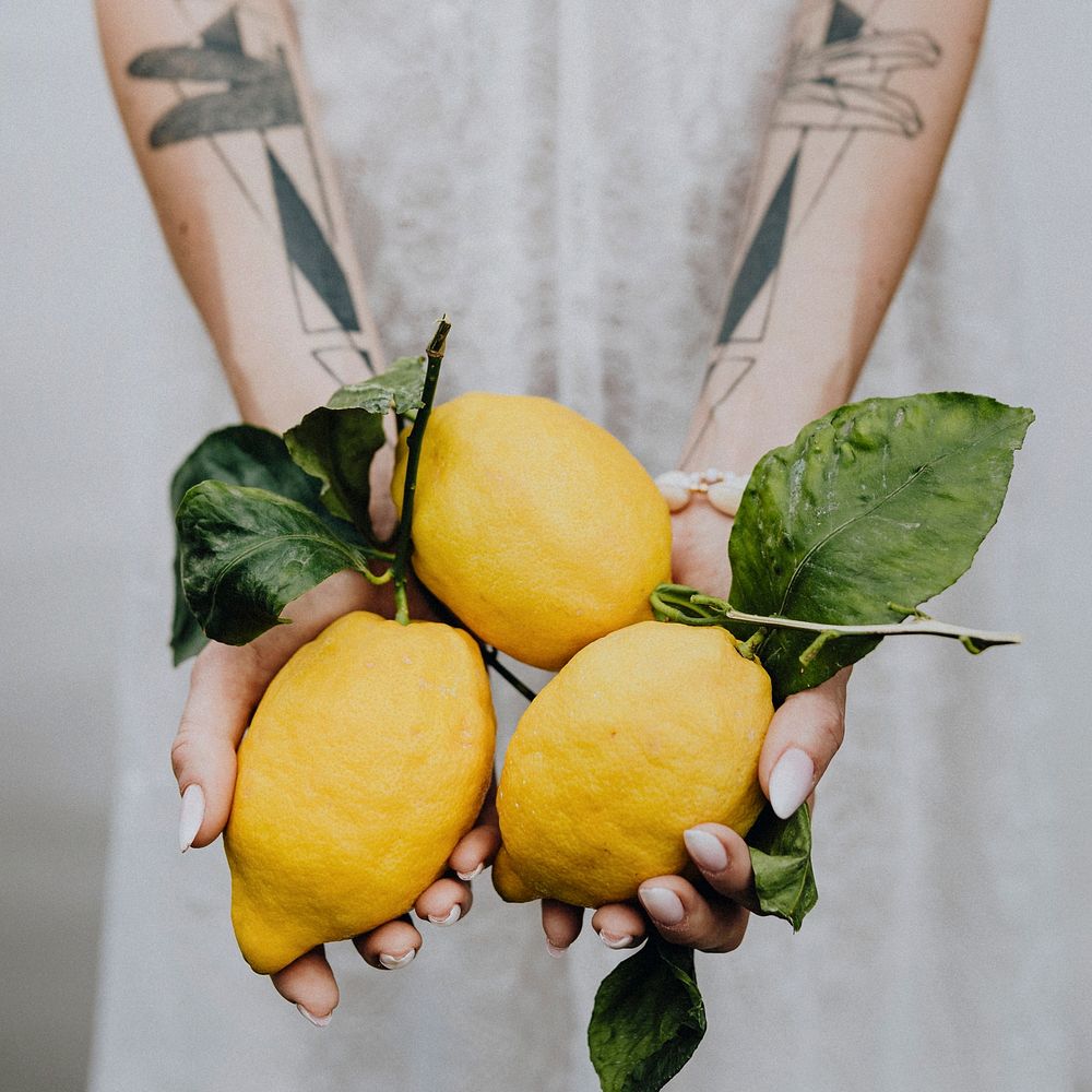 Tattooed hands holding fresh lemons