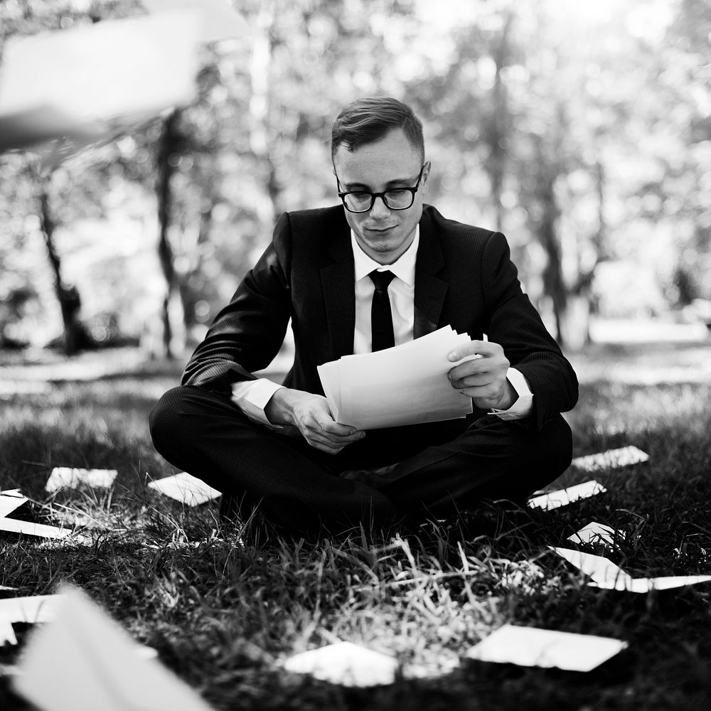 Businessman sitting on the grass reading some paperwork