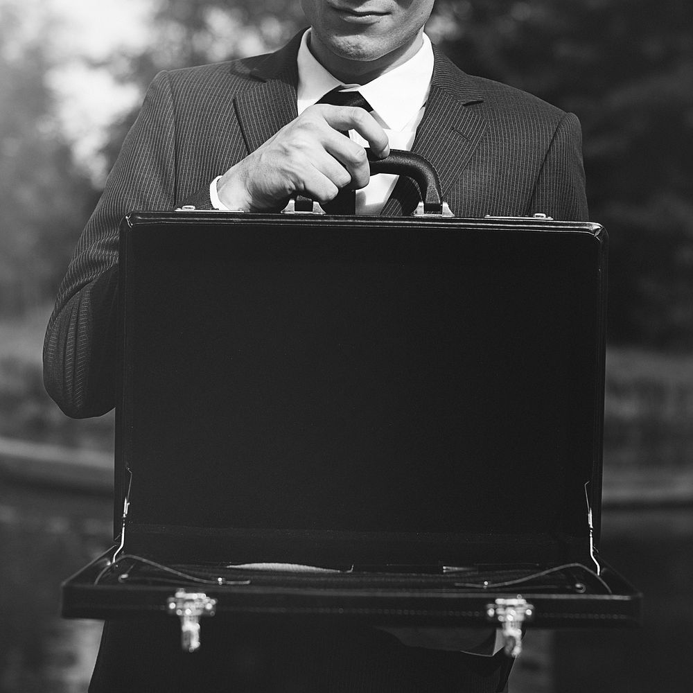 Businessman holding a suitcase in nature