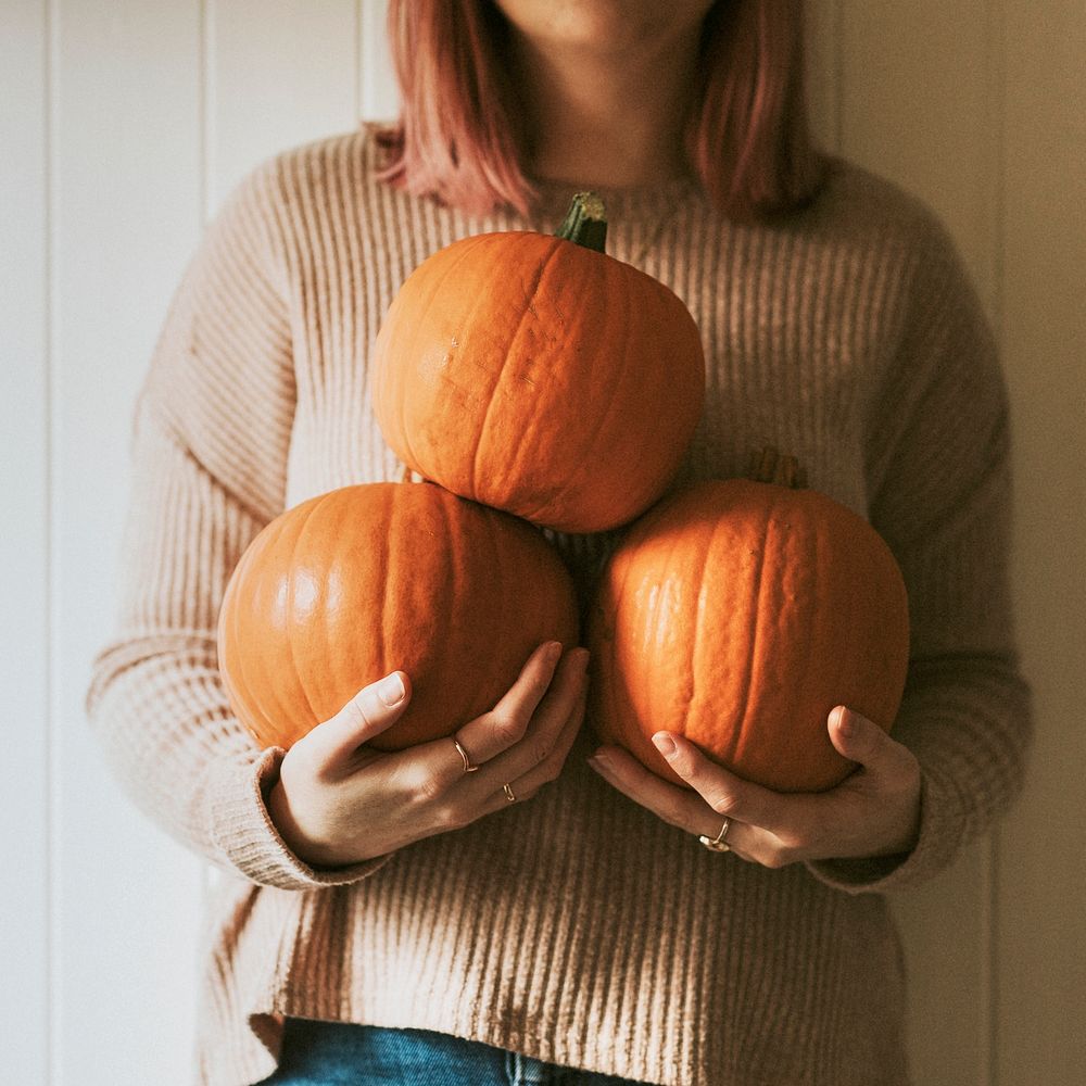 Woman holding Halloween pumpkins in a farmhouse
