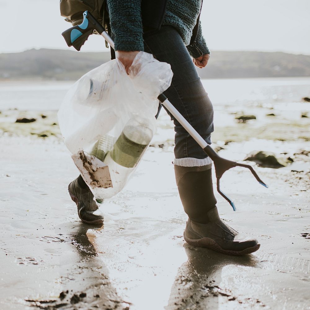 Beach cleanup volunteer carrying garbage bag for environment campaign