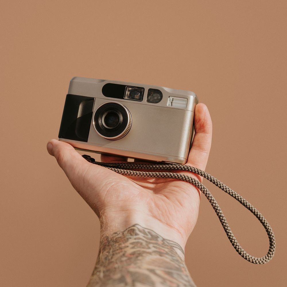 Retro analog film camera, held by tattooed photographer psd