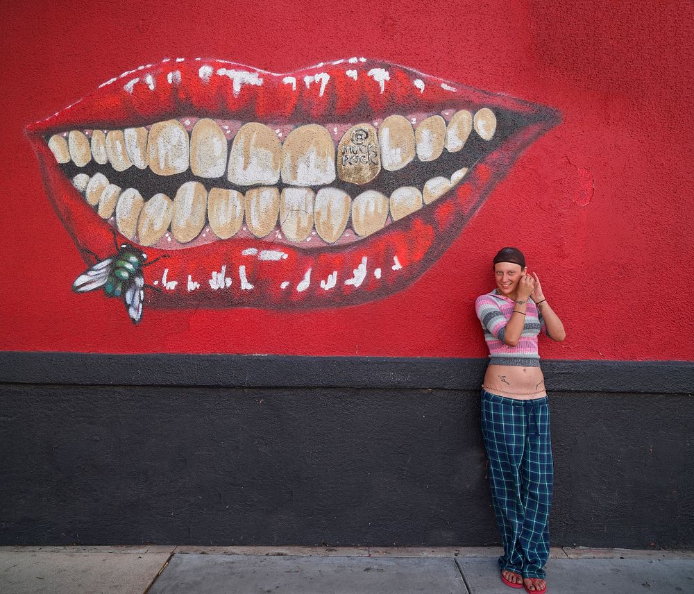 Courtney Ashby adjusts an earring near a memorable mural on historic Fourth Avenue, now home to many trendy restaurants and…