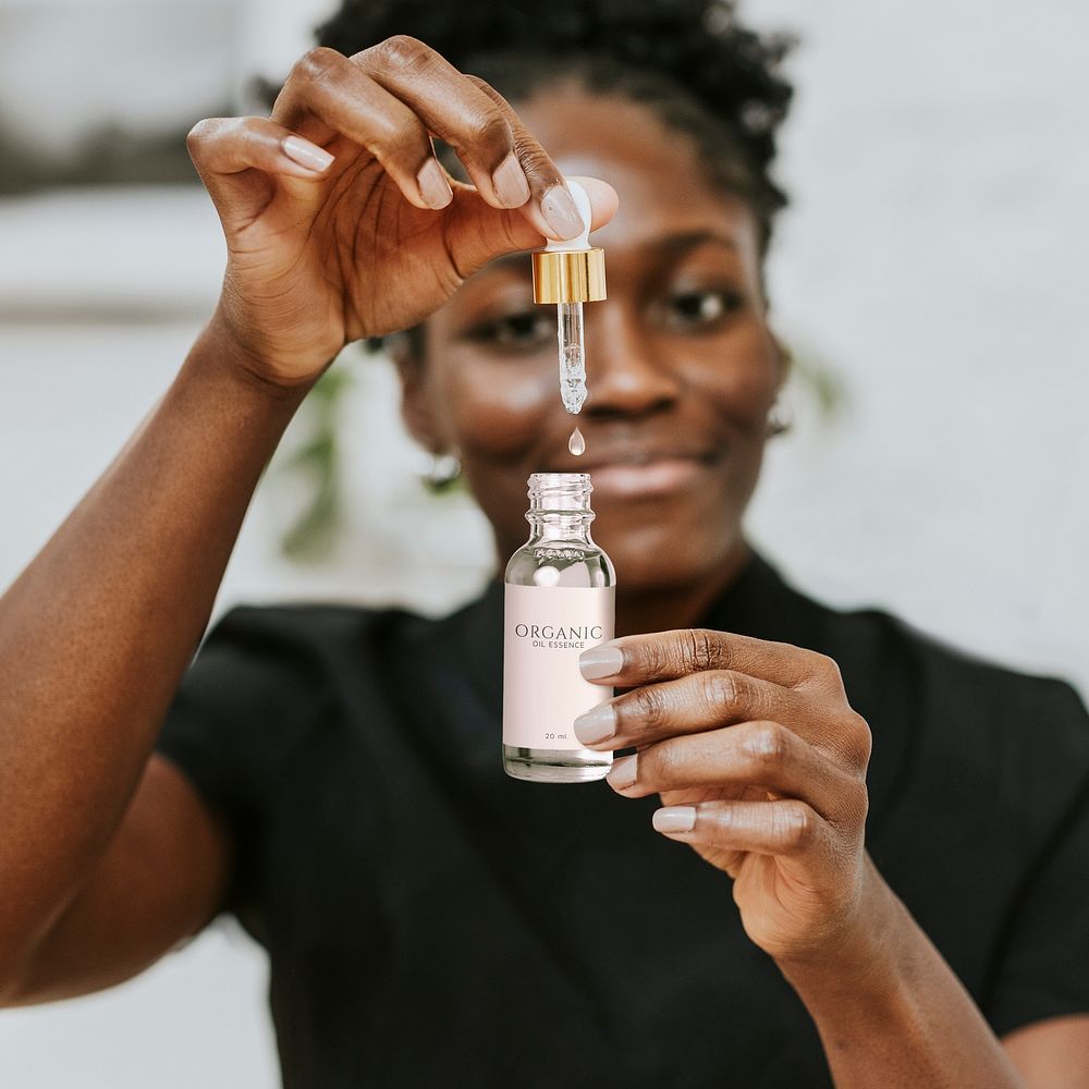 Dropper bottle mockup in African American woman&rsquo;s hands psd