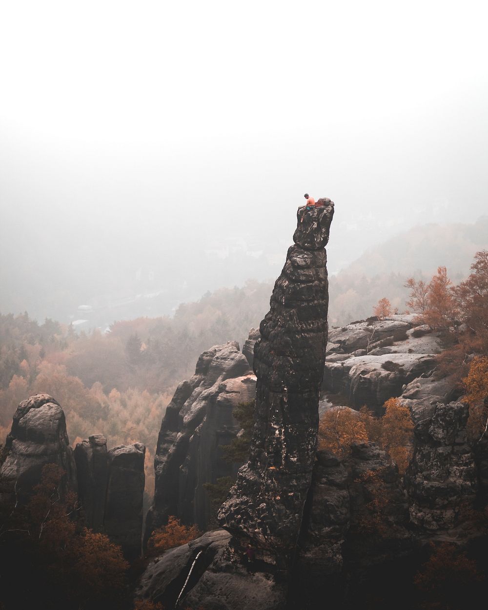 Climber on top of a needle rock at Elbe Sandstone Mountains in Czech Republic