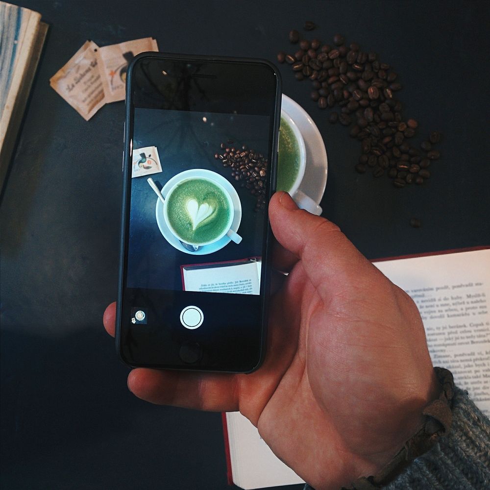 Man capturing an image of a Matcha latte with smartphone