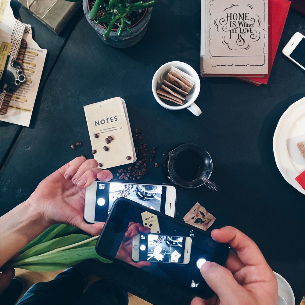 A man shooting a picture of  a cup of coffee with smartphone