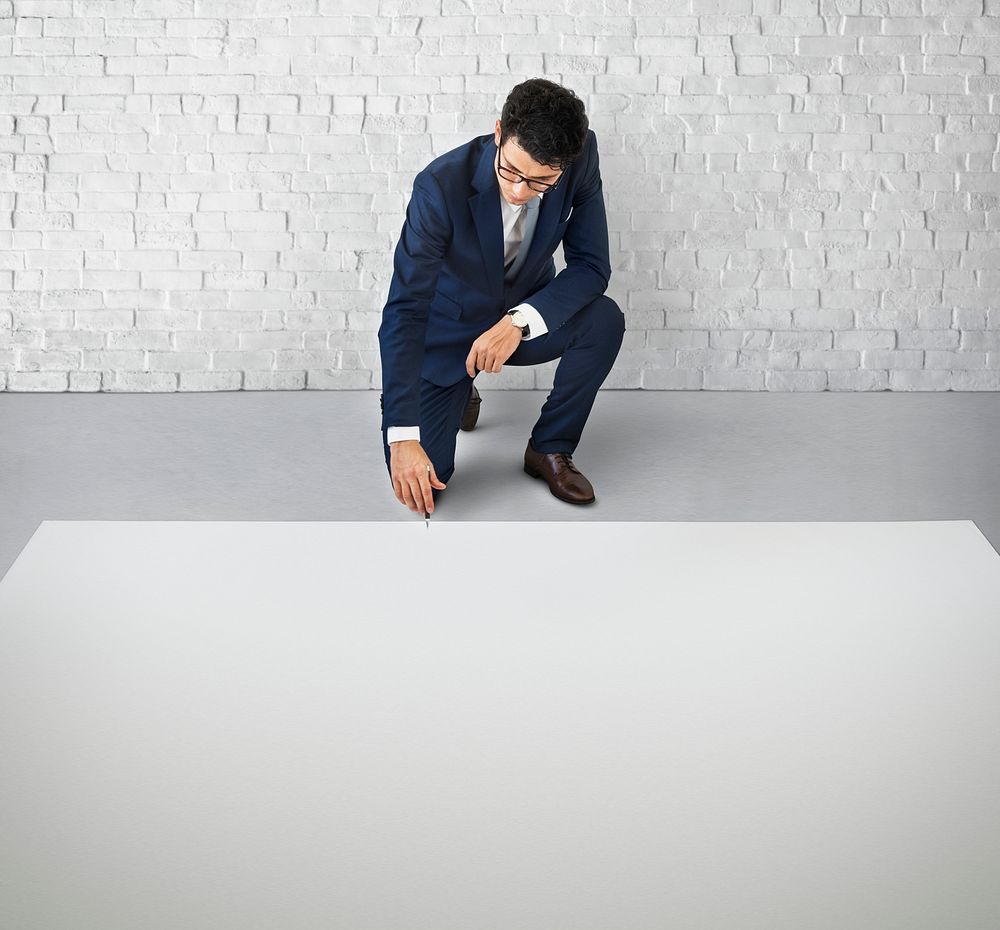 Businessman kneeling down on the floor with a big white copy space