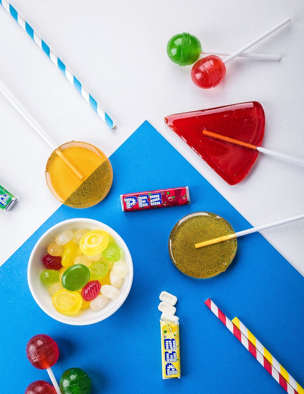 Lollipops with bowl of candies on white and blue background 