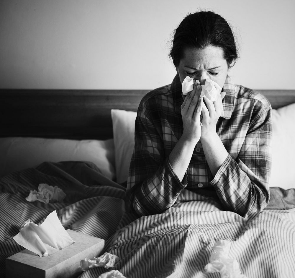 A sick woman sneezing in bed