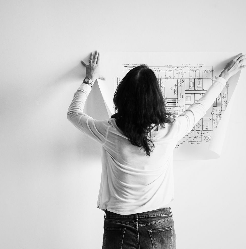 Woman showing building blueprint on the wall