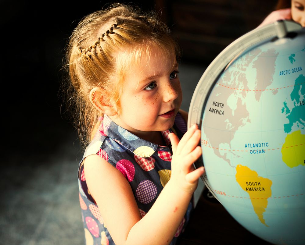Little girl searching on a globe