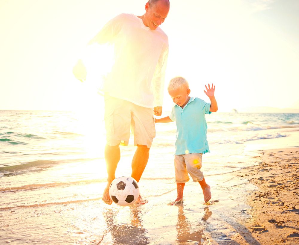 Father and son playing football at the beach