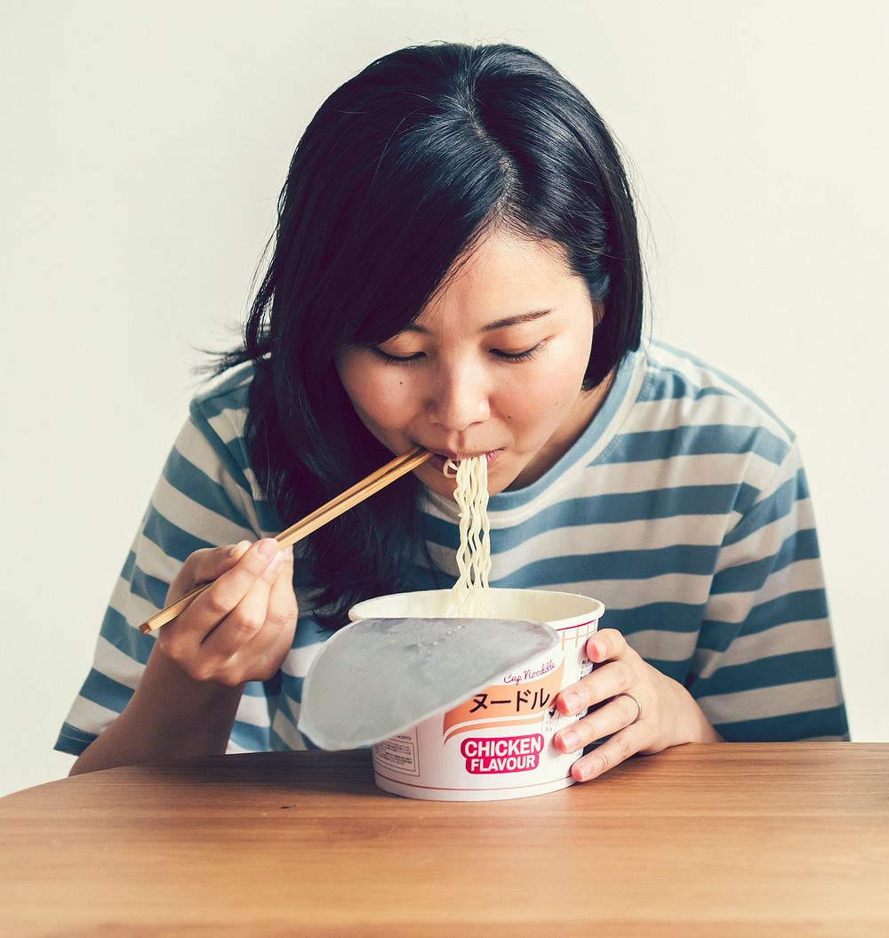 Asian woman eating instant noodles