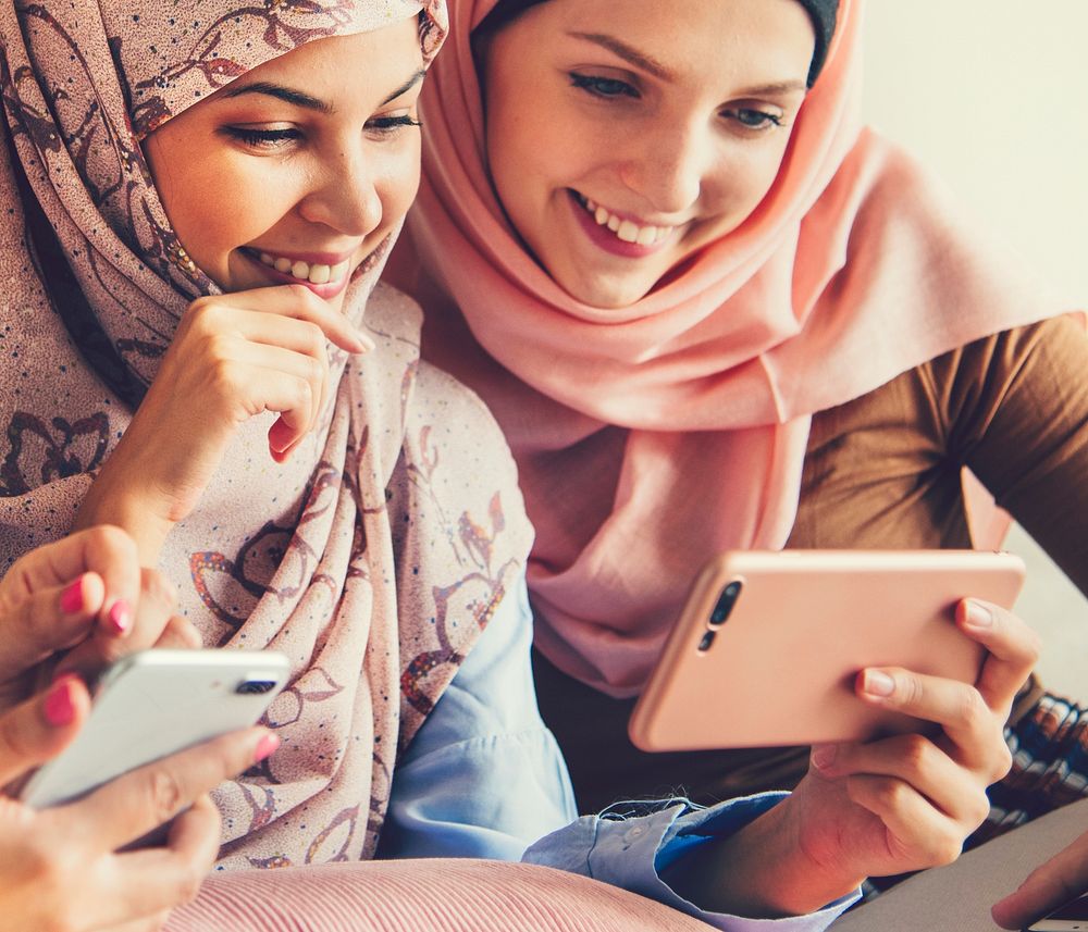 Muslim girls playing on a phone together
