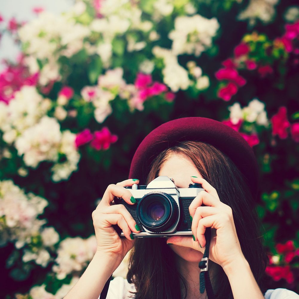 Girl in hat taking photos with a vintage camera