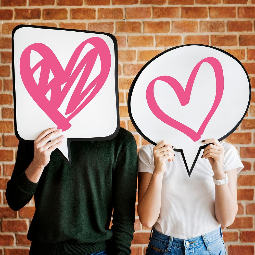 Young couple holding speech bubbles with heart icons
