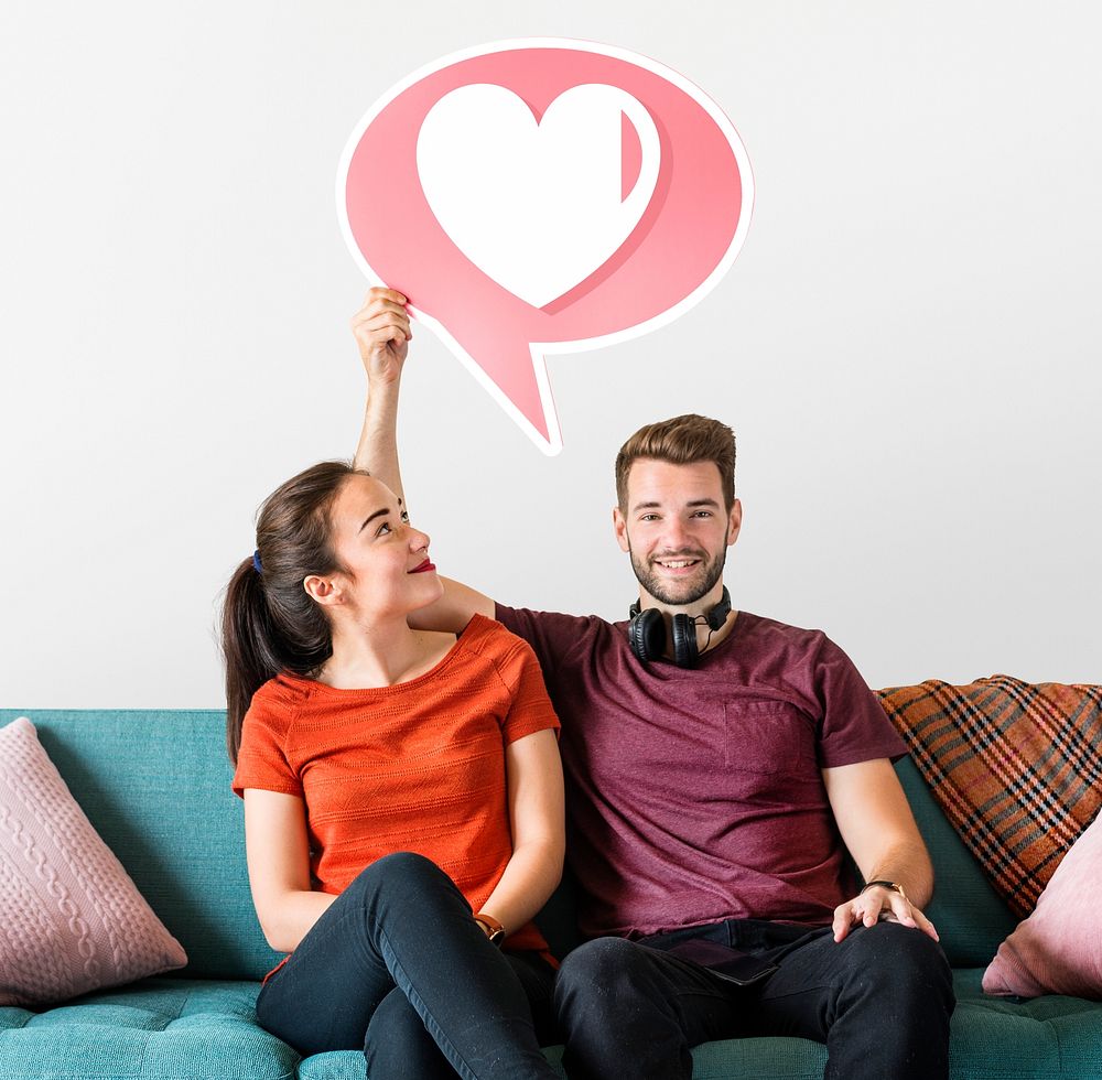 Cheerful couple holding a speech bubble with heart icon