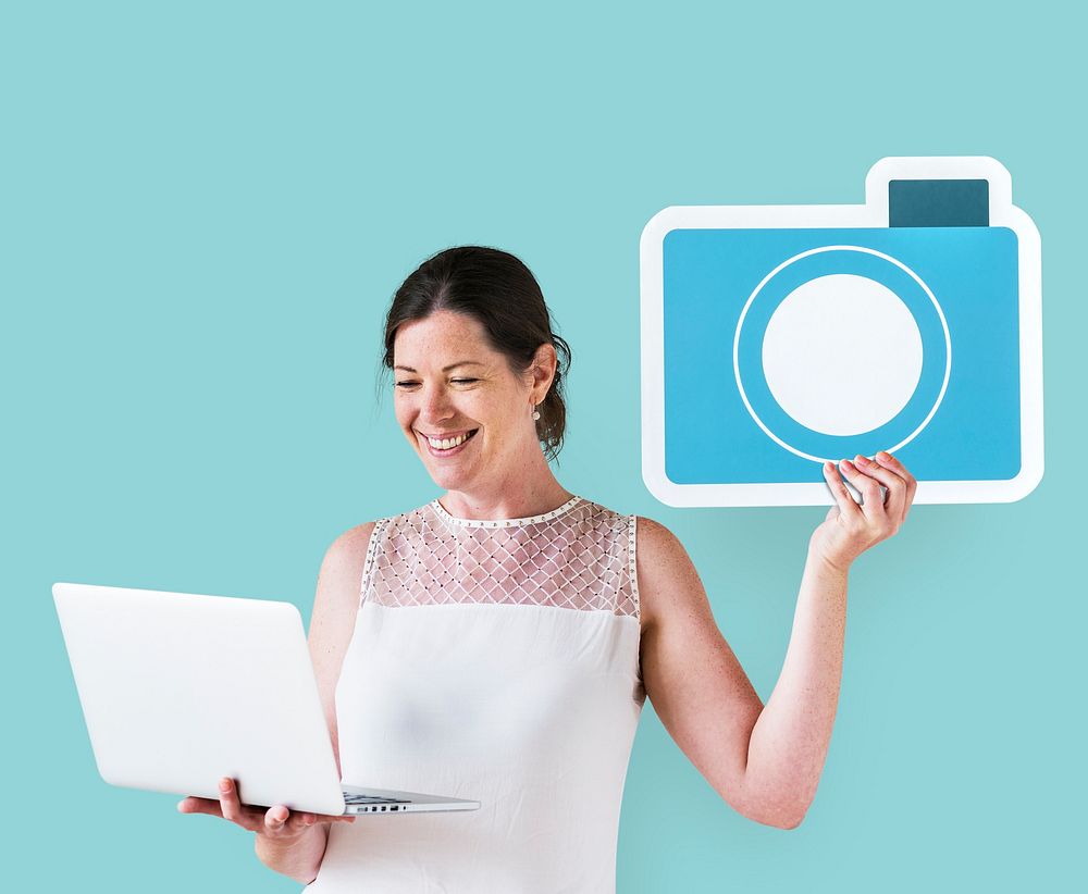 Woman holding a camera icon and using a laptop