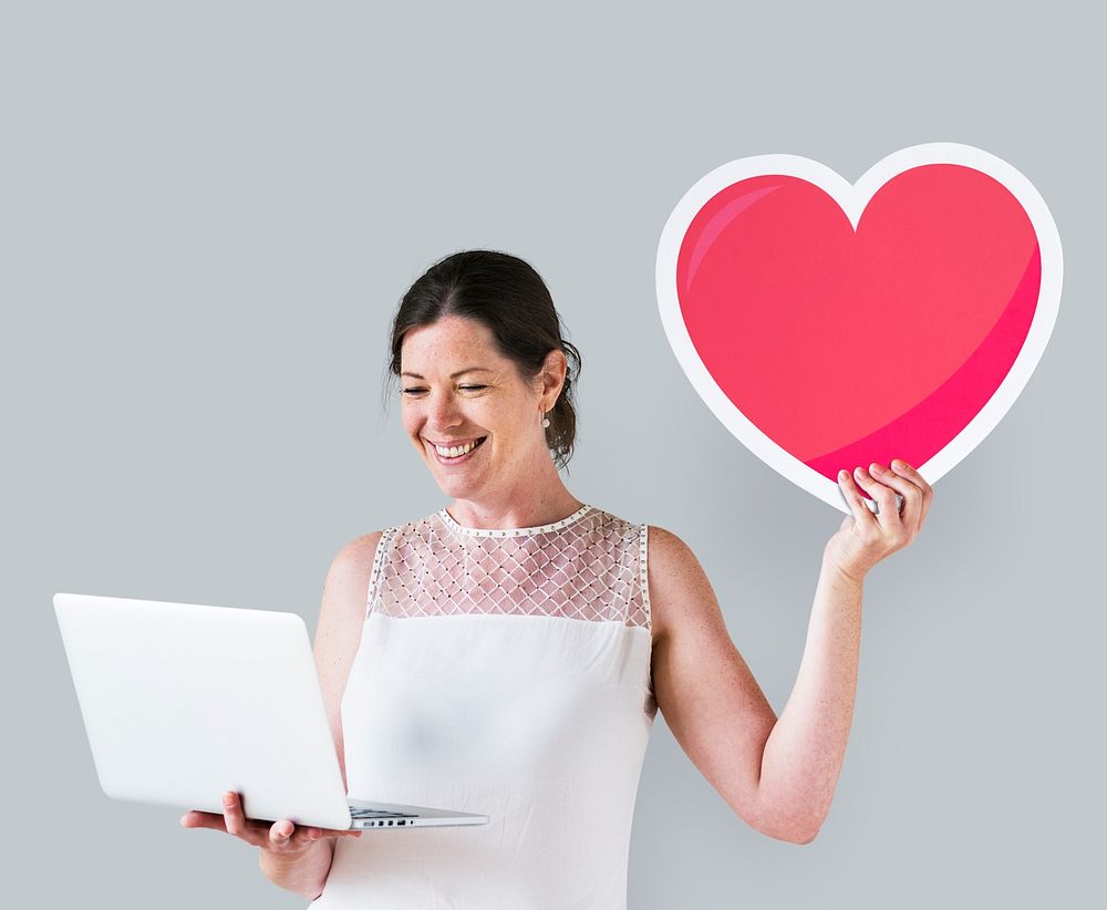 Woman showing a heart icon and using a laptop