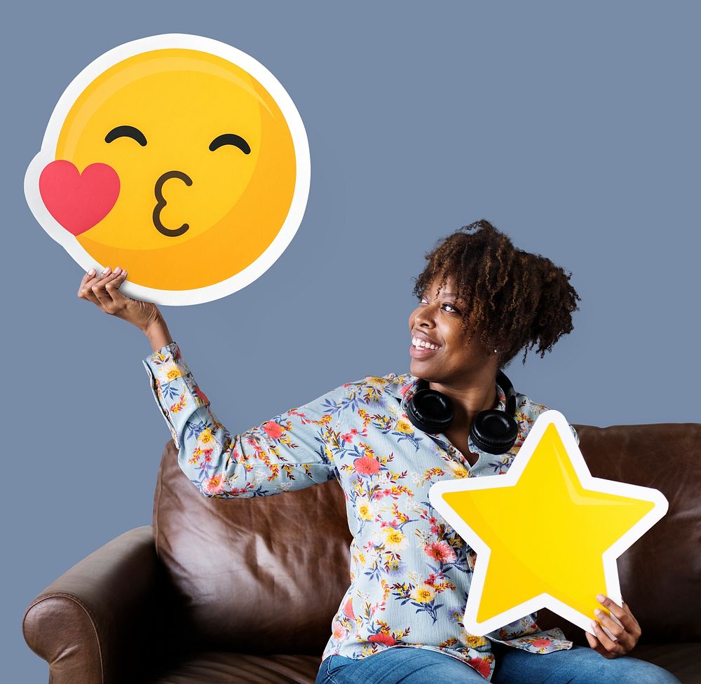 Cheerful woman holding a kissing emoticon and star icons