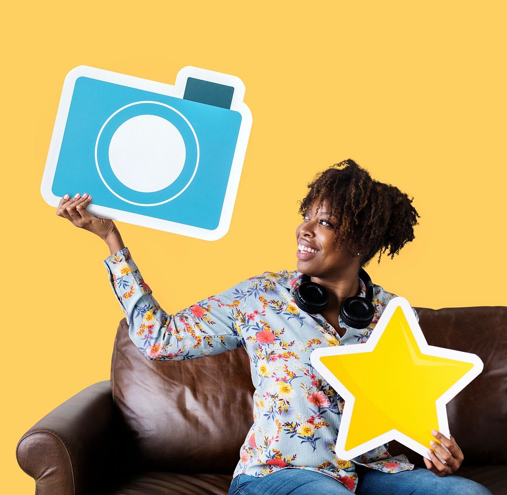 Cheerful woman showing blue camera icon on couch