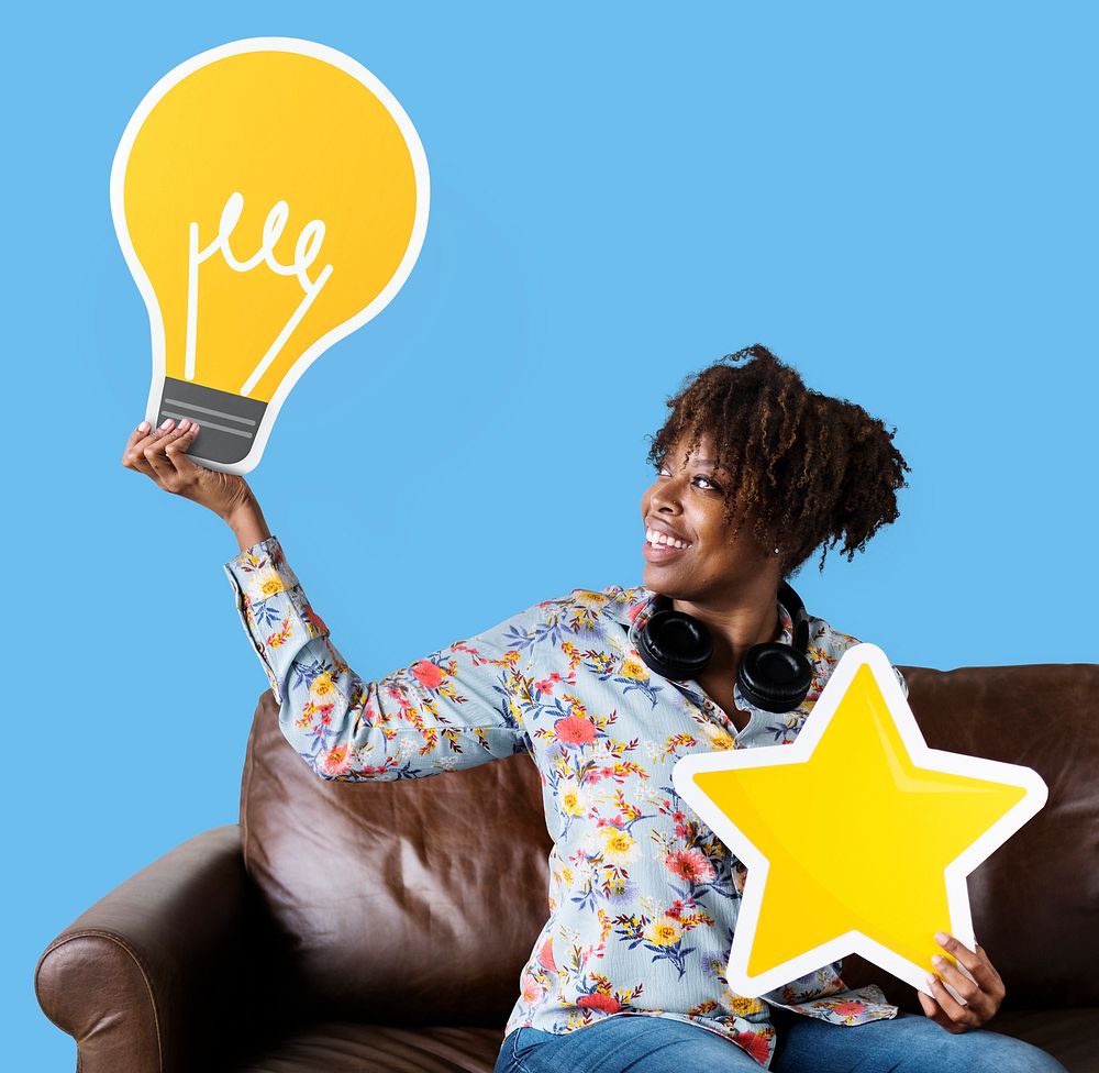 Cheerful woman showing light bulb icon on couch
