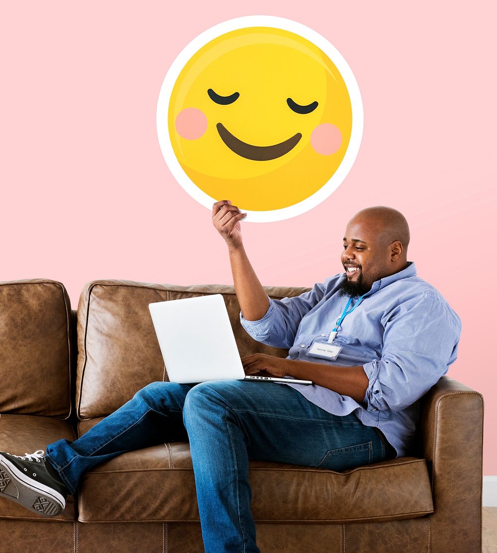 Man showing a blushing emoticon and using laptop