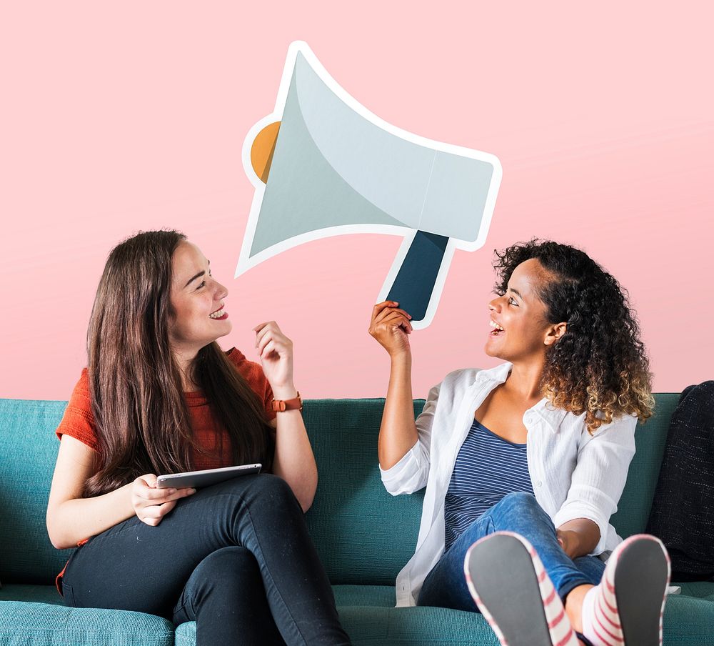 Cheerful women holding a megaphone icon on couch