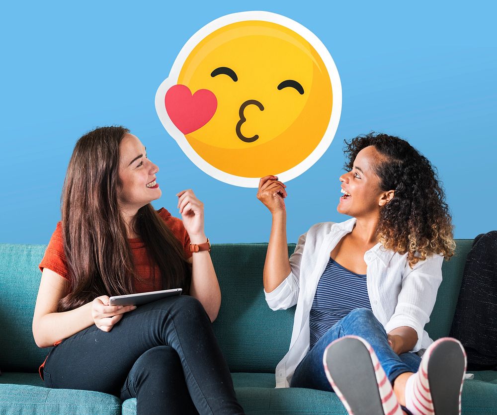 Cheerful women holding a kissing emoticon icon