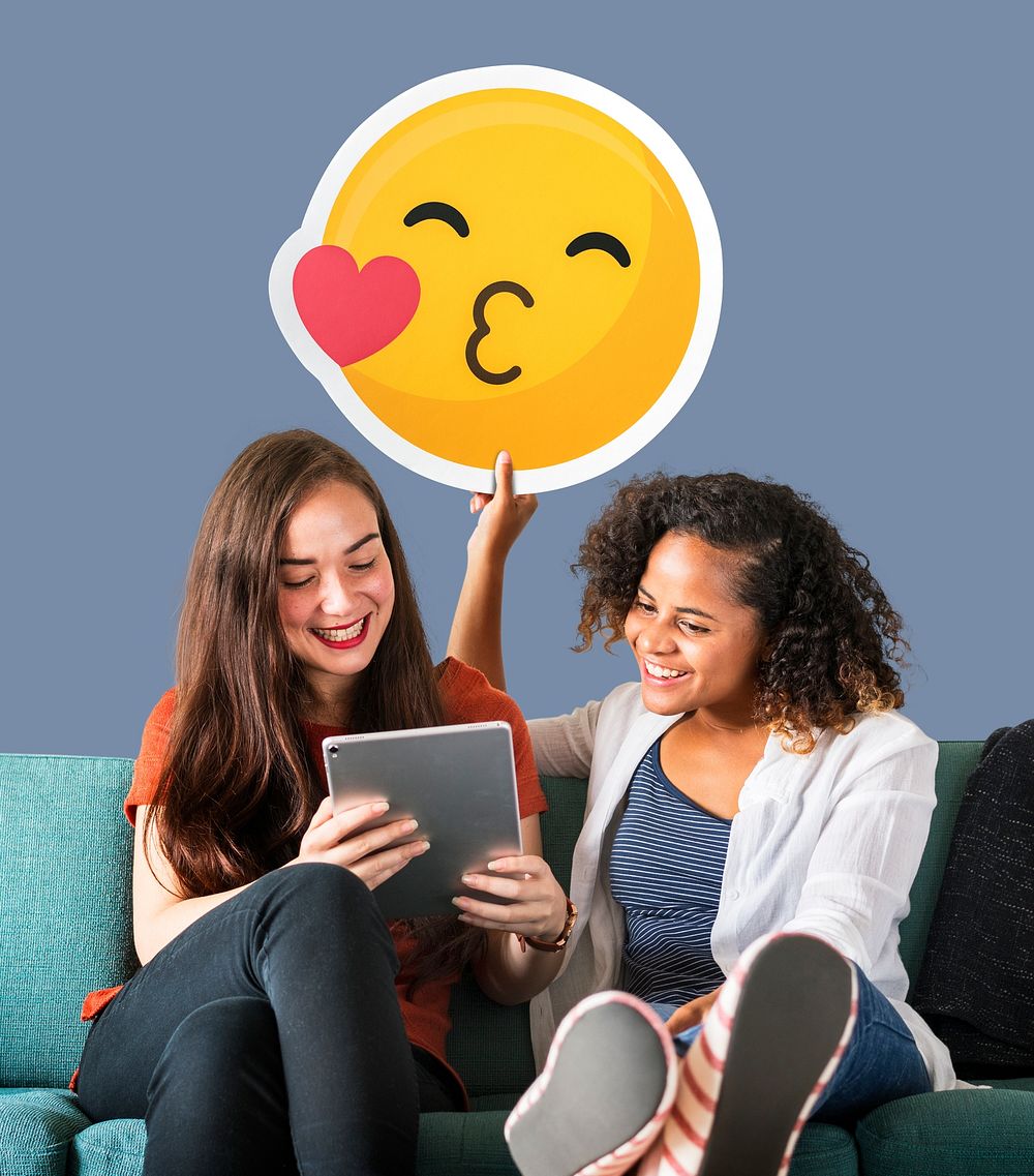 Women holding a kissing emoticon and using a tablet
