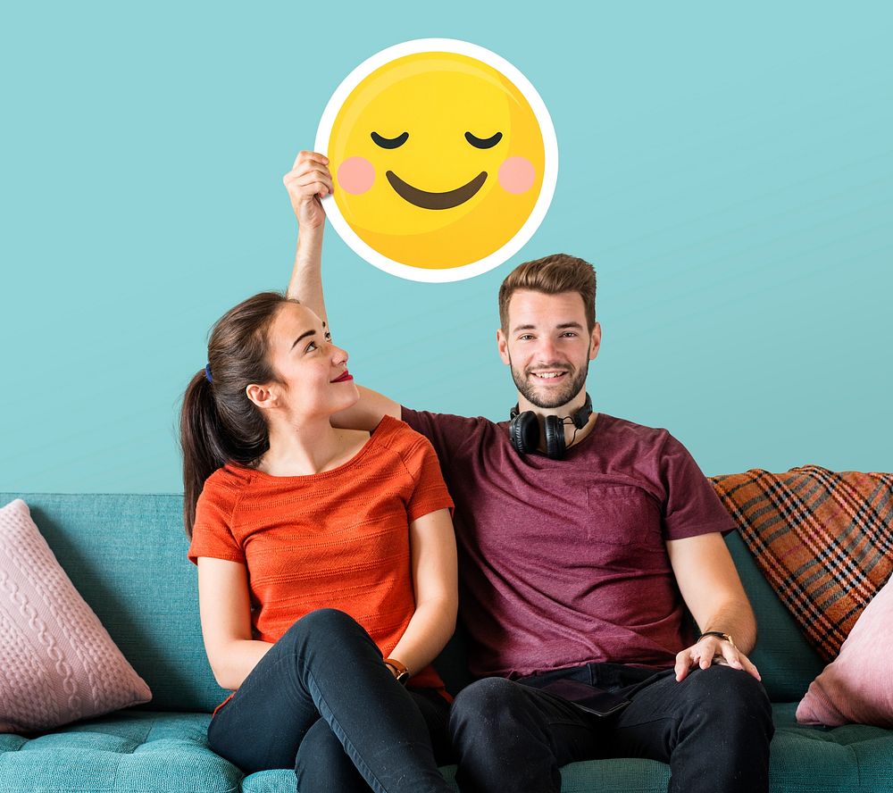 Cheerful couple holding a blushing emoticon