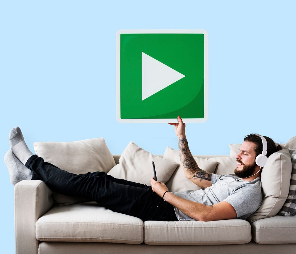 Male on a couch holding a play button
