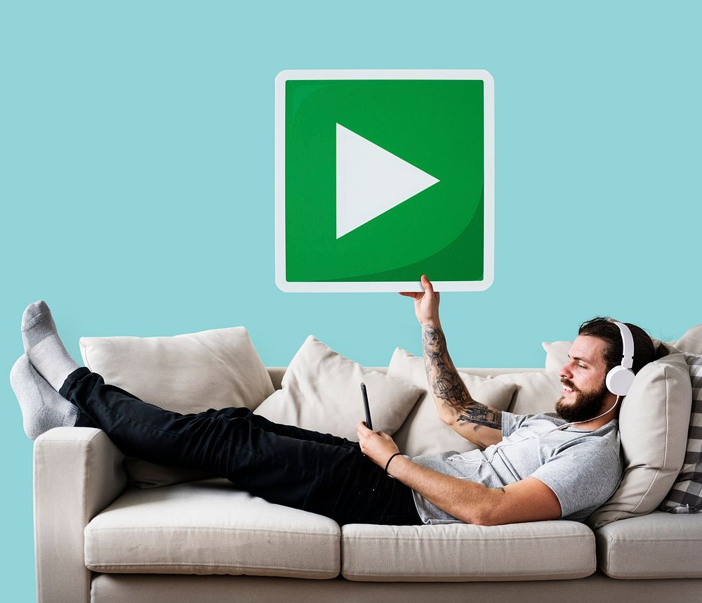 Male on a couch holding a play button