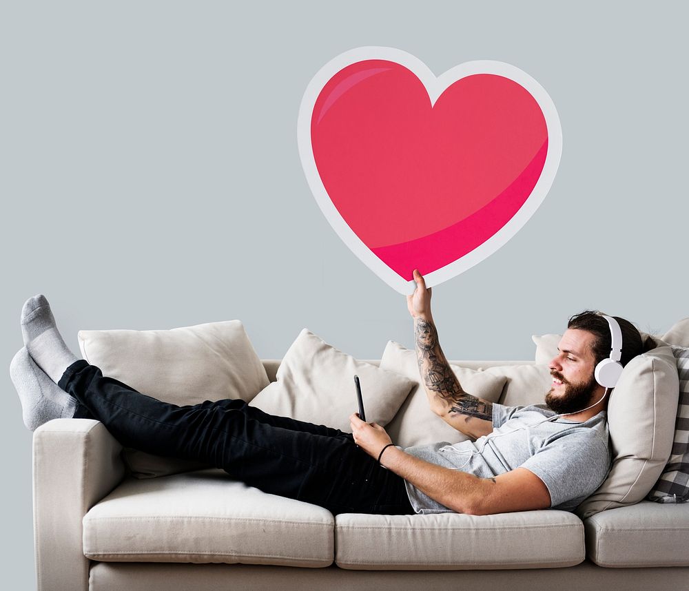 Male on a couch holding a heart emoticon