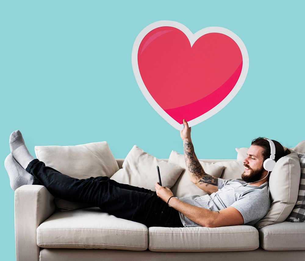 Male on a couch holding a heart emoticon