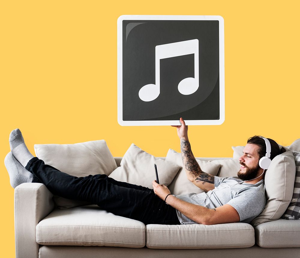 Male on a couch holding a musical note icon