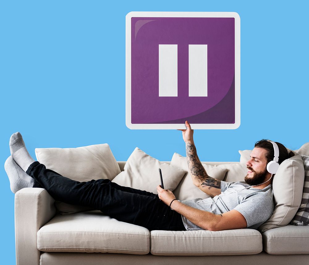 Male on a couch holding a pause button icon